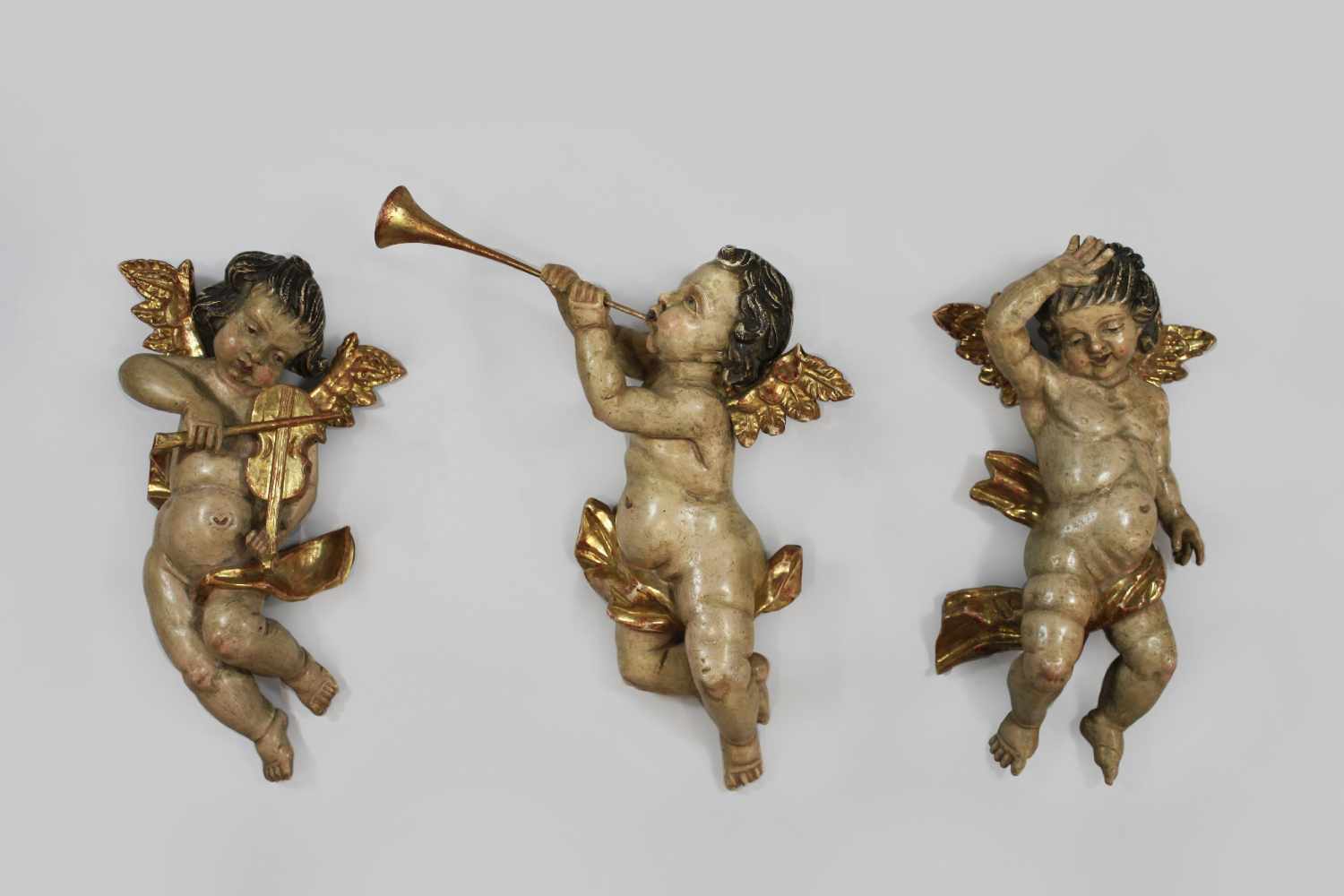 3 Putti, Holz, polychrom gefasst, mit goldenen Flügel, Instrumente n und Tuch, ein Putto mit