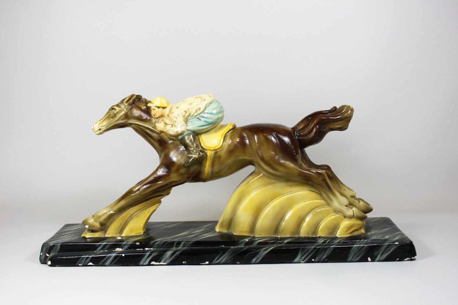 Jokey auf Pferd, Art Deco, Keramikfigur, auf rechteckigen Plinthe, polychrom gefasst. Maße: 60 x