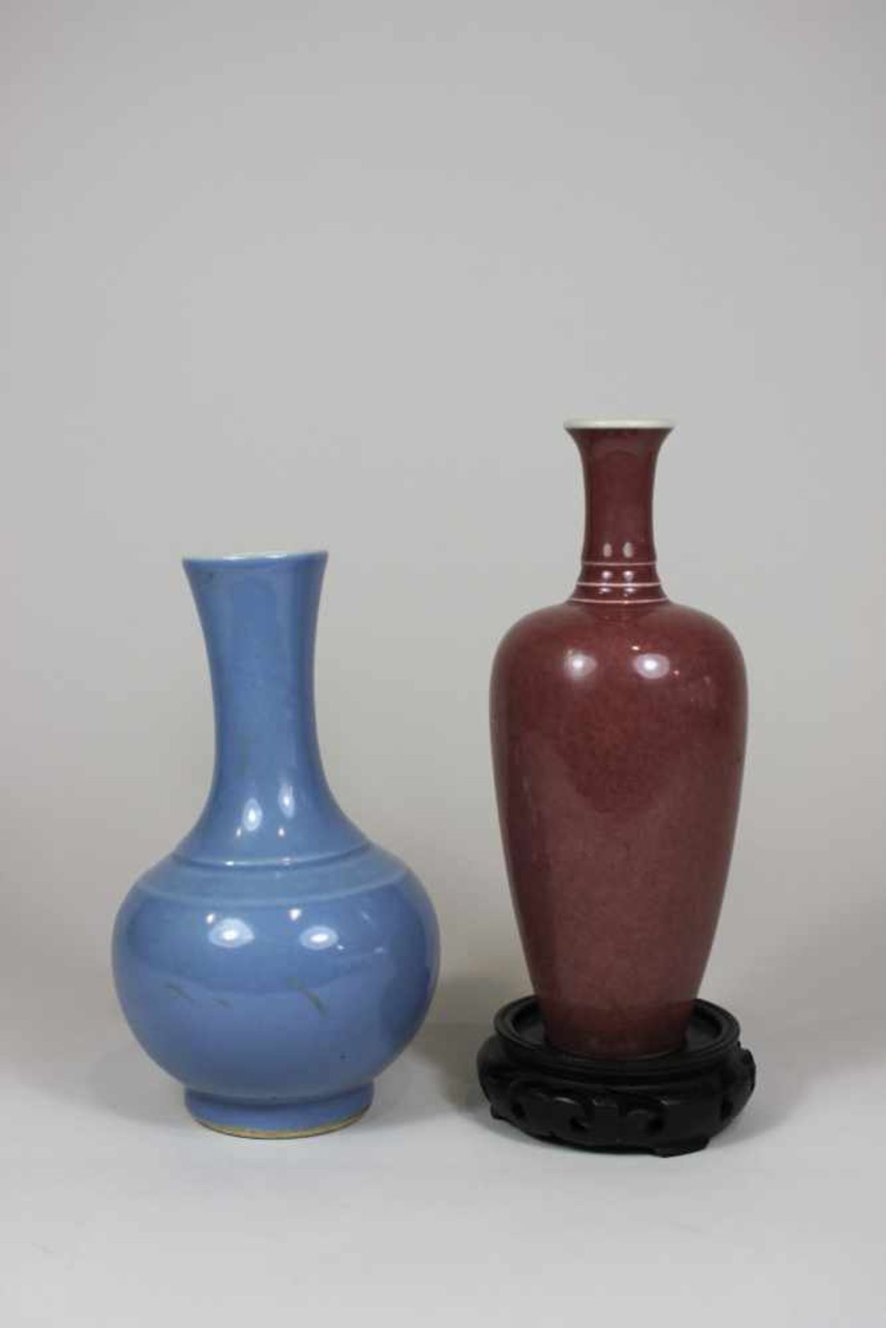 Zwei kleine Vasen, 19. Jh., 1. Vase, Porzellan, monochrom rot, H: 18 cm, auf rundem, geschnitztem