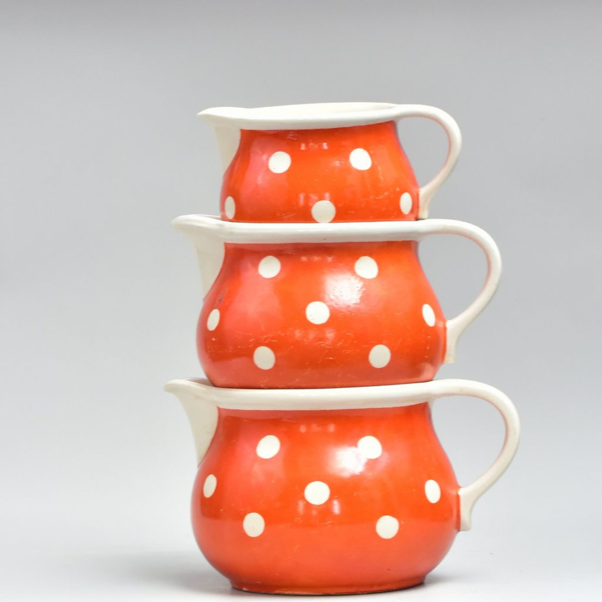 Drei Milchkrüge um 1950, orange mit weißen Punken, H 9-13 cm