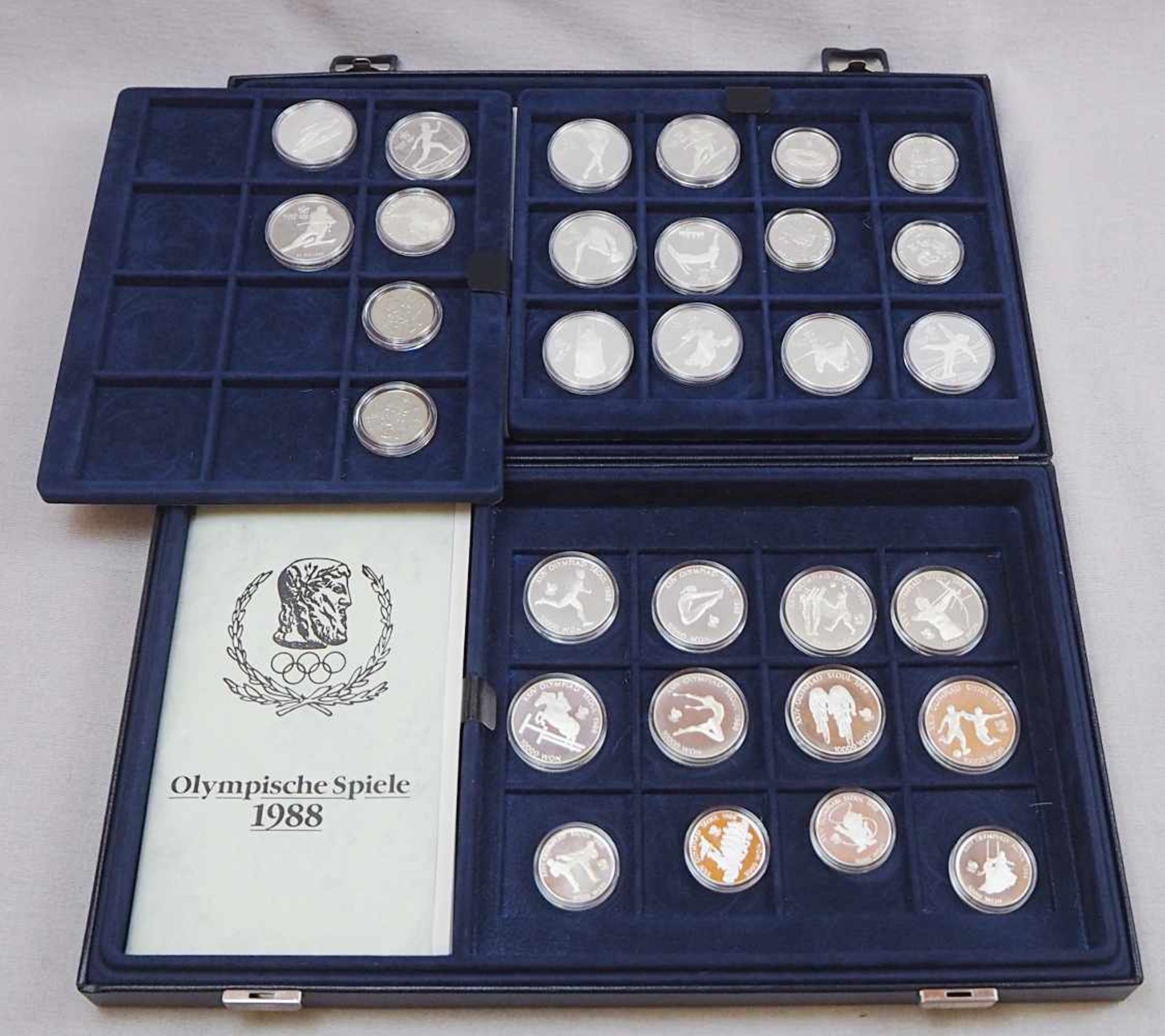 1 Konv. Münzen/MedaillenSi. u.a. BRD Gedenkmünzen, 10 DM, USA, Kanada, "Olympia", in 2 Etuis