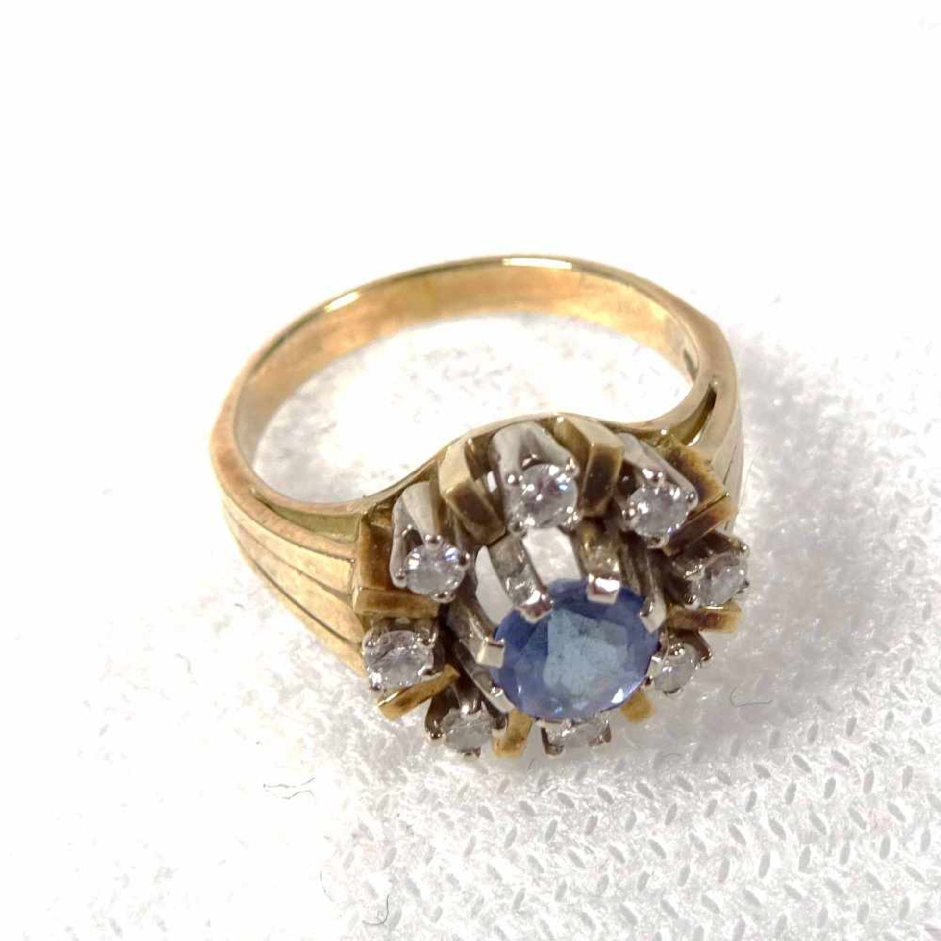Ring, 585 GG und WGbesetzt mit einem rund-facettierten blauen Farbstein von ca. 0,40 ct., umgeben