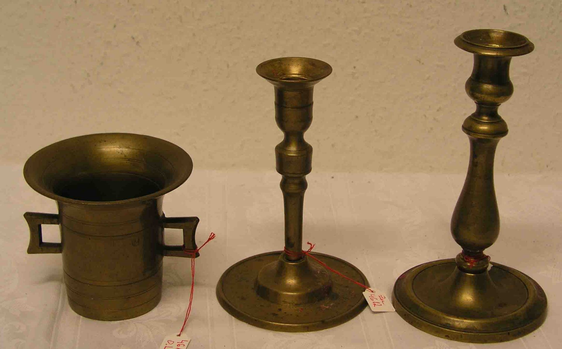 Mörser, Gelbguss, 19. Jh., Höhe: 10cm. Dazu zwei Kerzenleuchter, Messing, Höhen 17 und