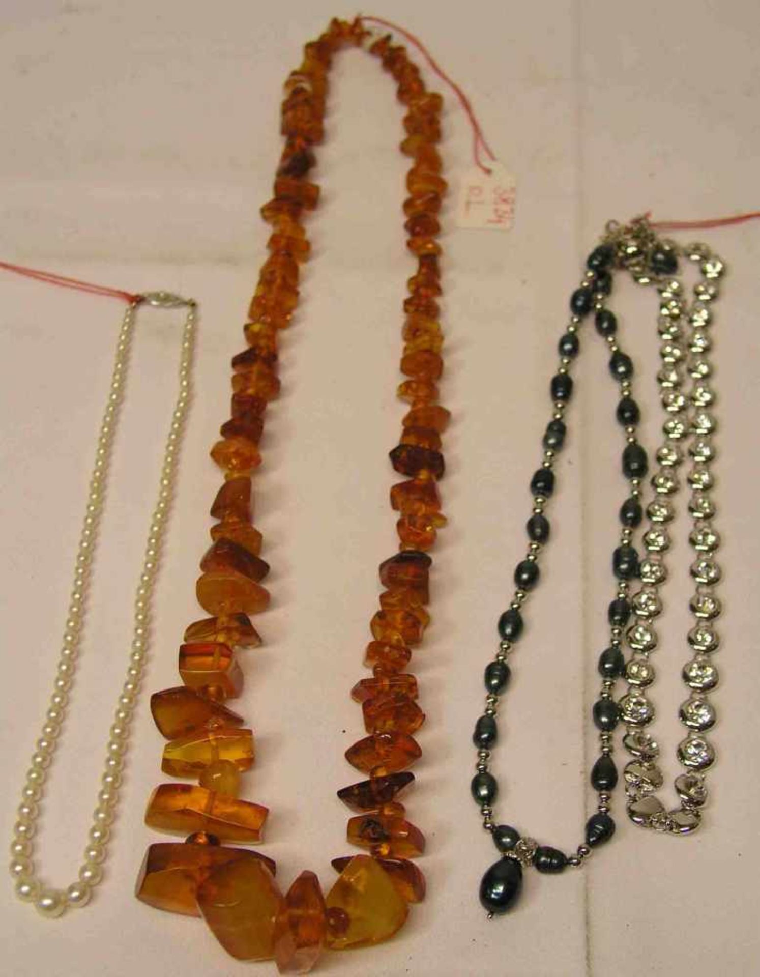 Vier Halsketten. Dabei: Bernstein, Länge: 62cm. Perlenkette mit 8 Kt. Goldverschluss.