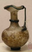 Kännchen, Oinochoe, römisch, 2. Jh. n. Chr. Leicht rötliches Glas mit Versinterungen.Umlaufender