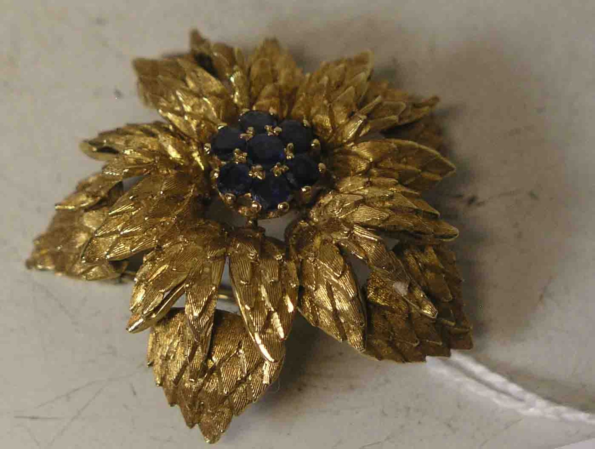Brosche in Blütenform. Gelbgold 18 kt. In der Mitte 7 Saphire. Durchmesser: 3,5cm. 15,9