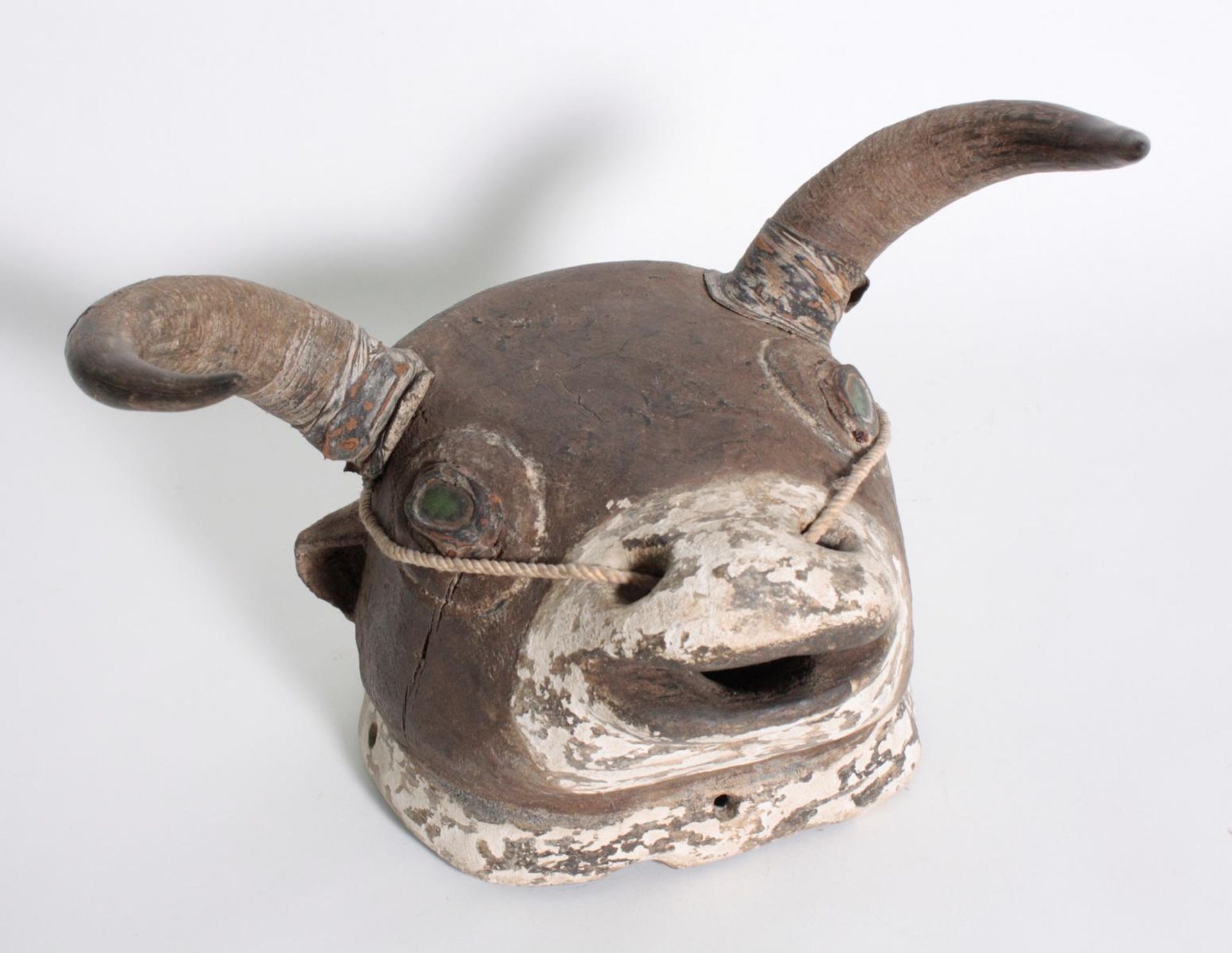 Bidjogo-Maske, Guinea BissauHolz in Form eines Bullenkopfes. Augen mit grüner Glaseinlage, echte