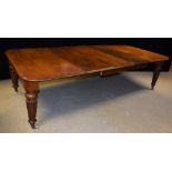 A Victorian oak extending dining table, rounded rectangular top, reeded tapered cylindrical legs,