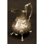 A 19th century silver cream jug, chased and repousse decoration, raised on three pad feet,