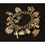 A silver charm bracelet, suspending twenty two charms inc Spaceman, Fan, Boat, Till, Dimple bottle,