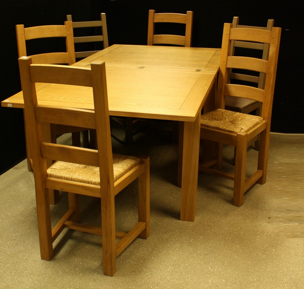A contemporary fold-out dining table; a set of four conforming rush seated dining chairs;