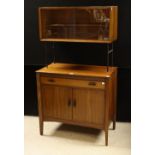 A retro mid-20th century sideboard, rectangular top with sliding glass doors enclosing a shelf,
