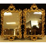 A pair of Rococo style ornate gilt framed wall mirrors, 133cm x 78.