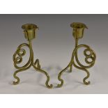 A pair of Arts and Crafts brass candlesticks, in the manner of W.A.S.