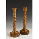 A pair of substantial turned oak candlesticks, large sconces above Solomonic pillars,