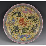 A Chinese circular charger, painted in the famille jaune pallete with dragons on a yellow ground,