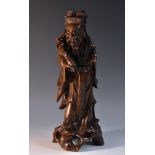 A Chinese hardwood figure, carved as an immortal holding a ruyi, his scrollinscribed with verse,