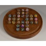 A collection of 19th century coloured opaque twist marbles, arranged on a mahogany solitaire board,