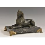 A French dark patinated metal desk model, of a sphinx, gilt metal mounted rectangular marble base,