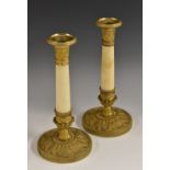 A pair of French Empire gilt metal and alabaster candlesticks, detachable engine-turned nozzles,