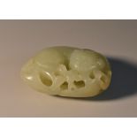 A Chinese celadon jade carving, of a stylized beast amongst blossoming prunus,