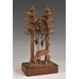 A Black Forest novelty timepiece, carved as a deer grazing beside pine trees, 24.