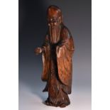 A Chinese rootwood figure, of a bearded immortal, he stands, wearing long robes, 32cm high,