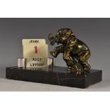 An Art Deco desk calendar, with a standing Elephant calf rearing, curled trunk,