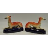 A pair of late 19th/early 20th century Staffordshire recumbent greyhounds