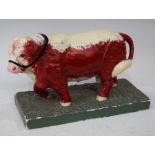 A Butchers shop window display model of a standing bull, red and white head, red body,