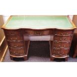 A Reprodux reproduction mahogany writing desk, leather inlaid serpentine top,
