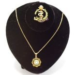 A 9ct gold circular pierced work pendant set with a central pearl and surrounded with round