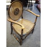 An oak open armchair, circular cane work back with carved leaf cartouche, shaped arms,