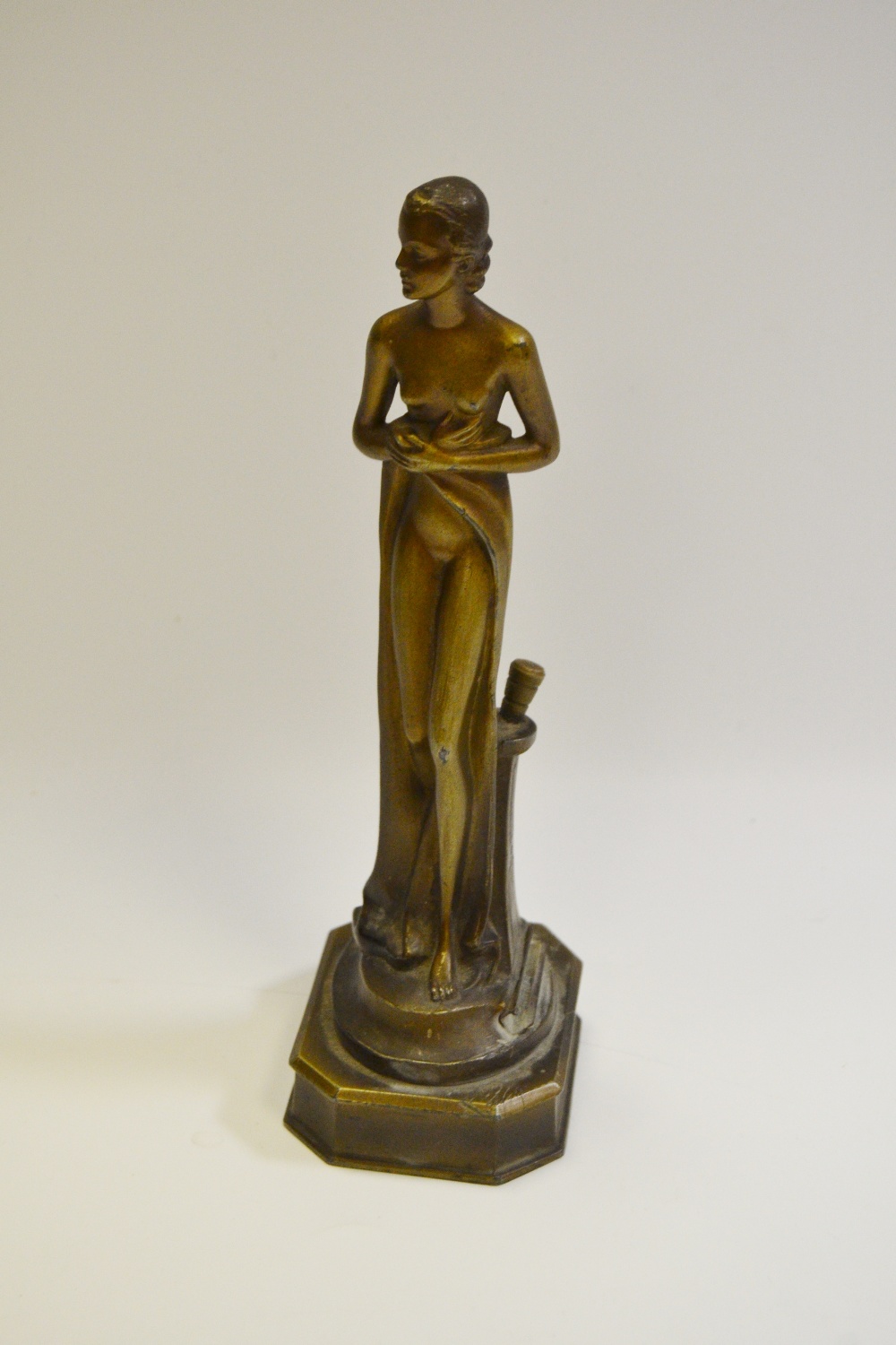 An Art Deco spelter match striker, as a scantily clad maiden, canted rectangular base,