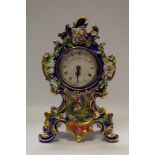 A porcelain mantel clock profusely decorated with colourful flora on cobalt ground.