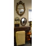 A heraldic gouache picture; an oval wall mirror; another; a gilt framed oval wall mirror;