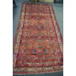 A hand woven Middle Eastern carpet geometric centre panel with banded border. 273cm x 133cm.