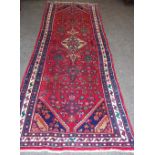 A hand woven Middle Eastern runner, geometric designs and floral motifs in hues of green, pink,