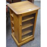 An Ercol DVD/CD cabinet glazed door to front, enclosing shelving,