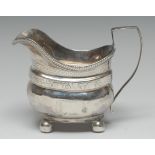 A George III silver boat shaped cream jug, engraved with band of strapwork and scrolling foliage,