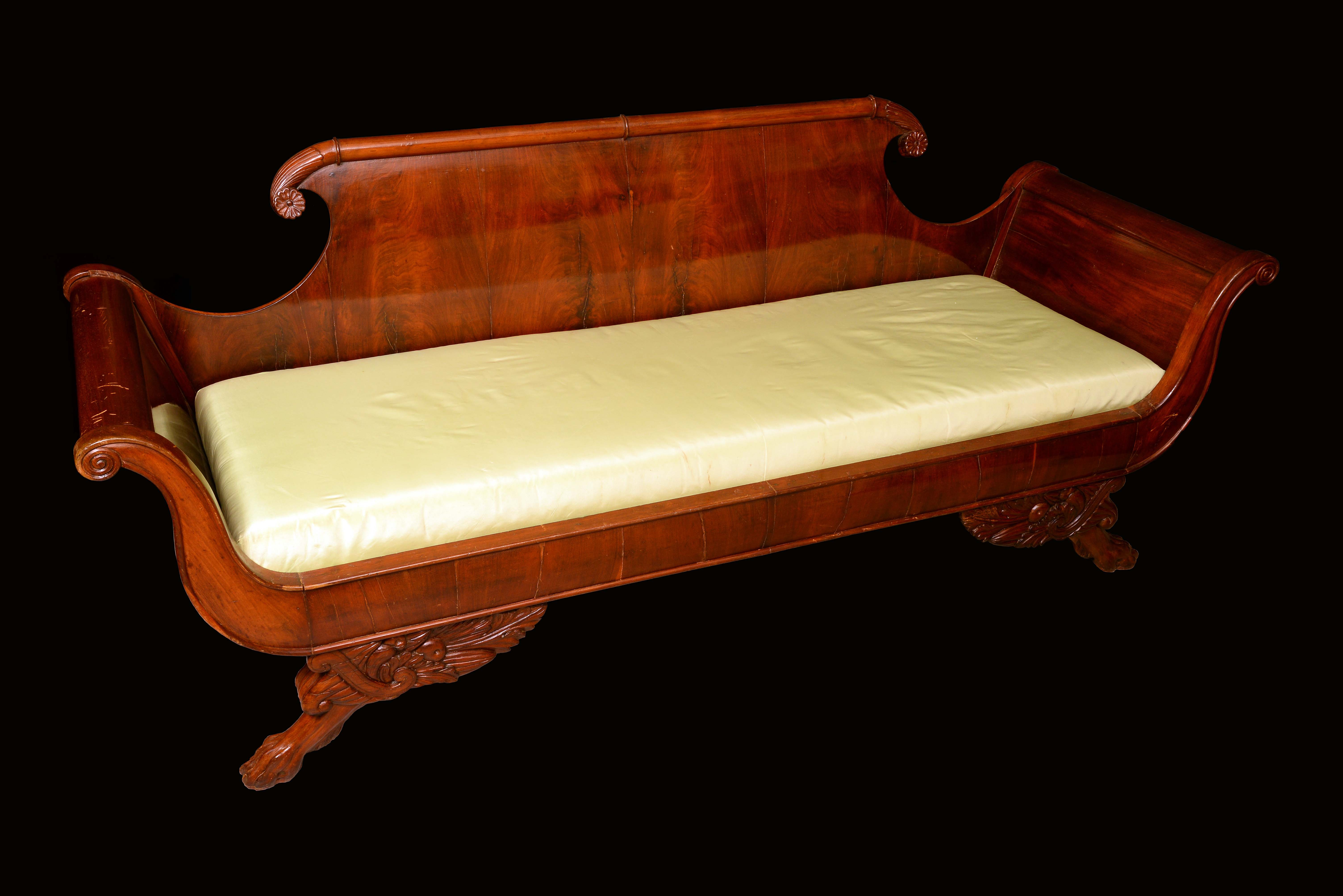 A French Empire mahogany scroll end sofa, shaped back terminating in flowerhead bosses,