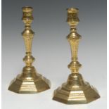 A pair of early 18th century French brass octagonal candlesticks, chased with flowerheads,