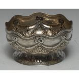 A Victorian silver sugar bowl, undulating lip, embossed ribbon bow swag above foliate body and foot,