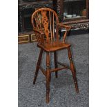A 19th century elm and ash child's Windsor high chair, arched back with wheel splat, saddle seat,