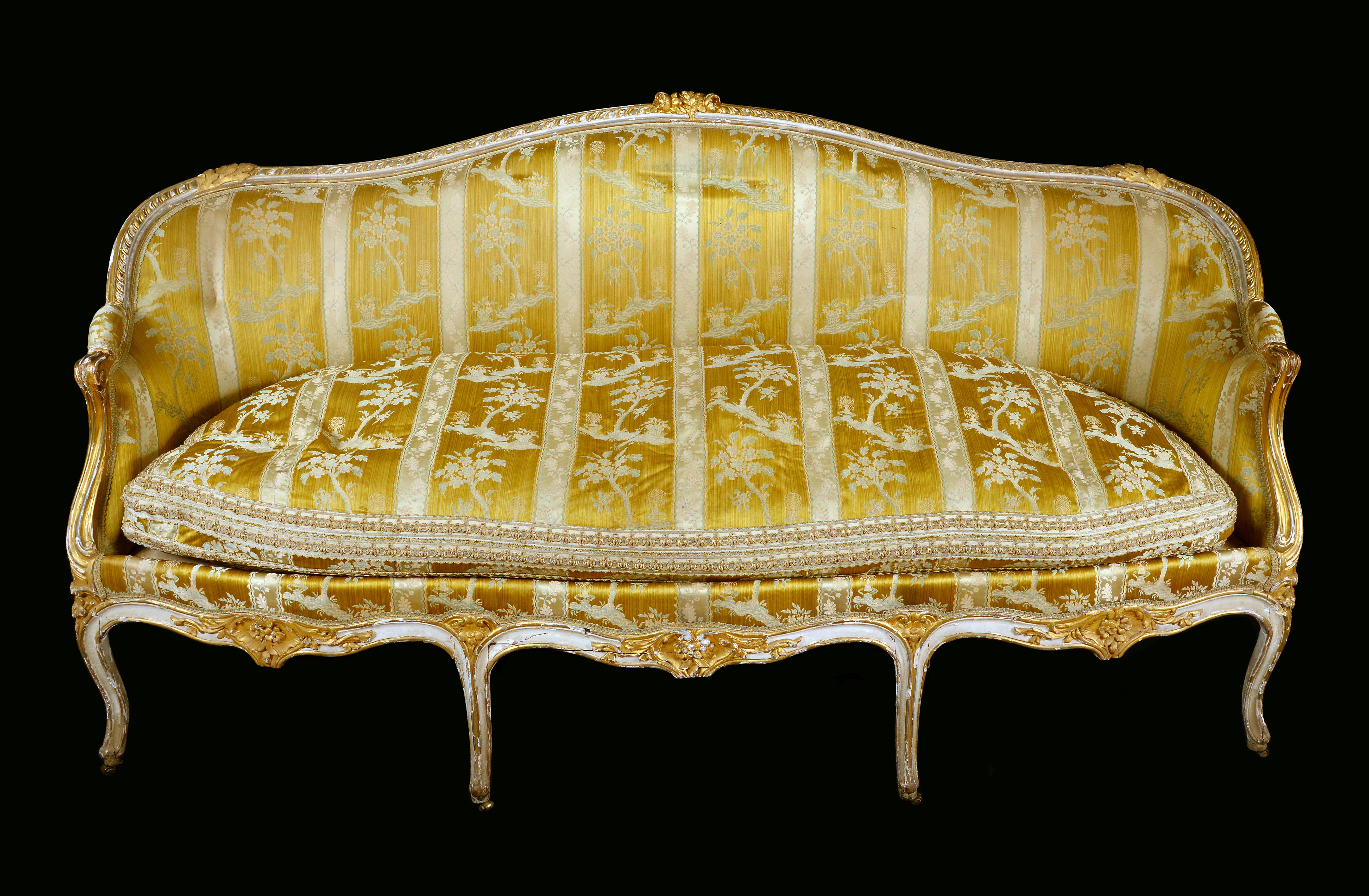 A mid 18th century French giltwood sofa, serpentine cresting rail terminating in scroll arms,