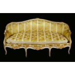 A mid 18th century French giltwood sofa, serpentine cresting rail terminating in scroll arms,