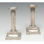 A pair of George V silver fluted Corinthian column candlesticks, detachable nozzles,
