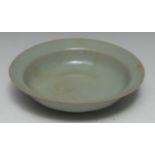 A Chinese celadon circular dish, the exterior moulded in shallow relief with lotus leaves,