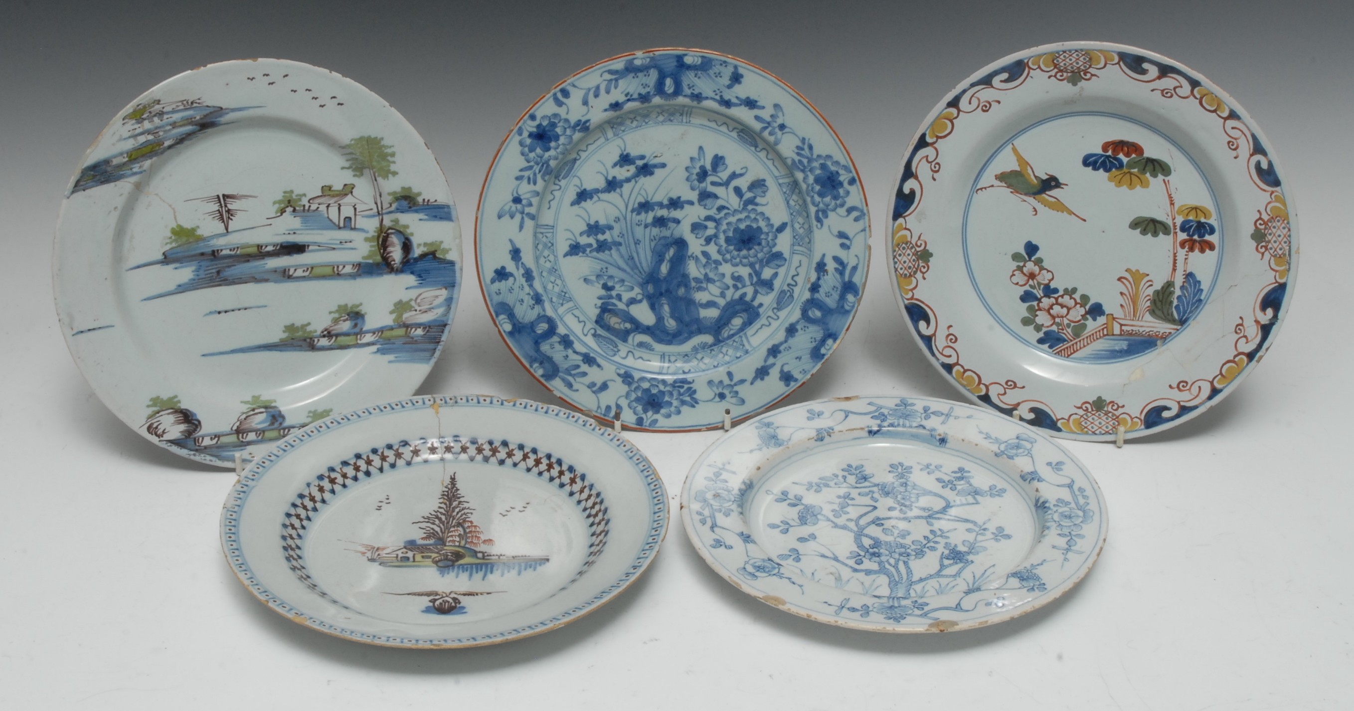 An 18th century Delft circular plate, painted with a stylized Chinese landscape in tones of blue,