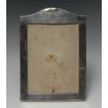 A George V silver shaped arched rectangular easel photograph frame, of military interest,
